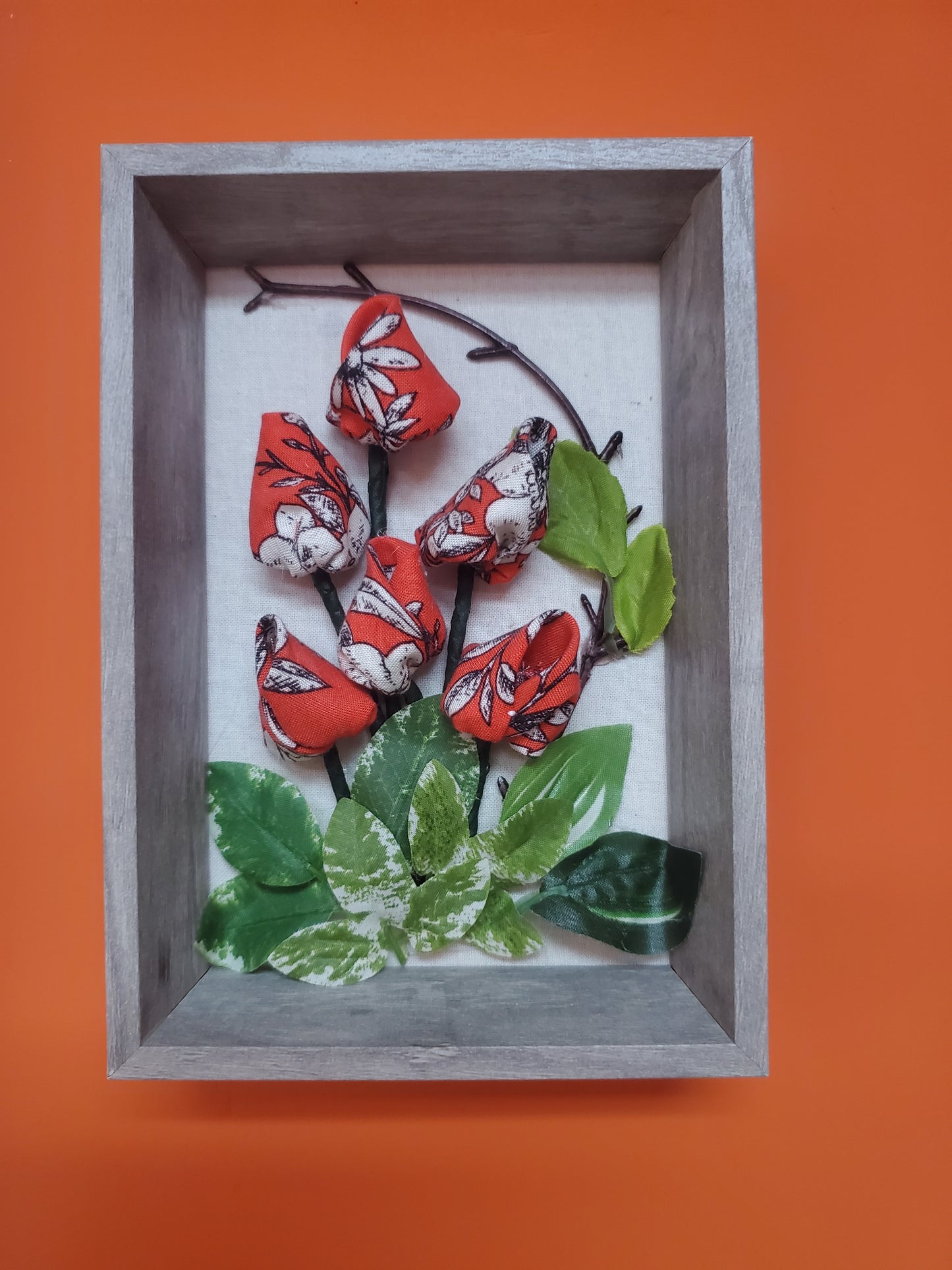 Handmade flowers and green leaves, put them in a picture frame, flowers are made of fabric.