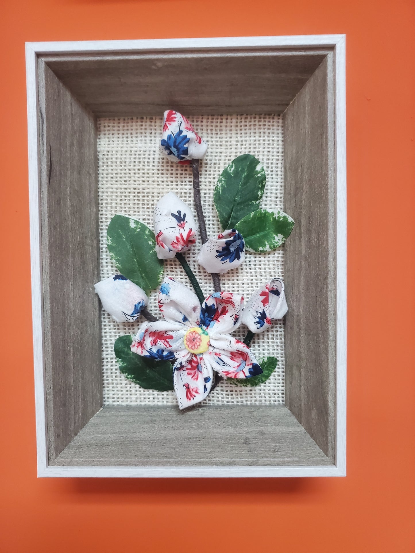 Handmade flowers and green leaves, put them in a picture frame, flowers are made of fabric.