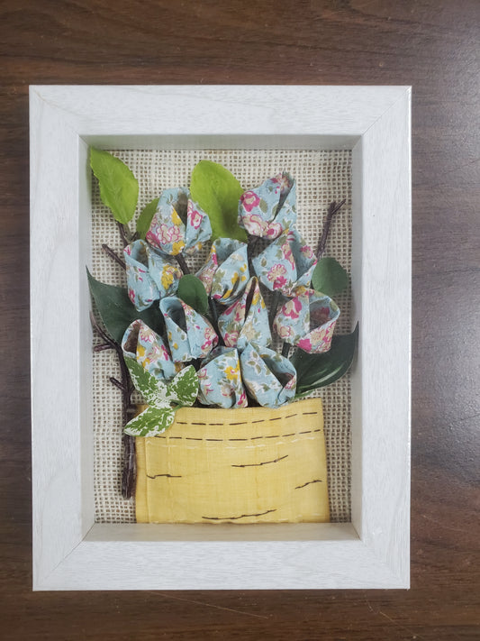 Handmade flowers with sky blue flower pots and green leaves, put them in a picture frame, flowers are made of fabric.