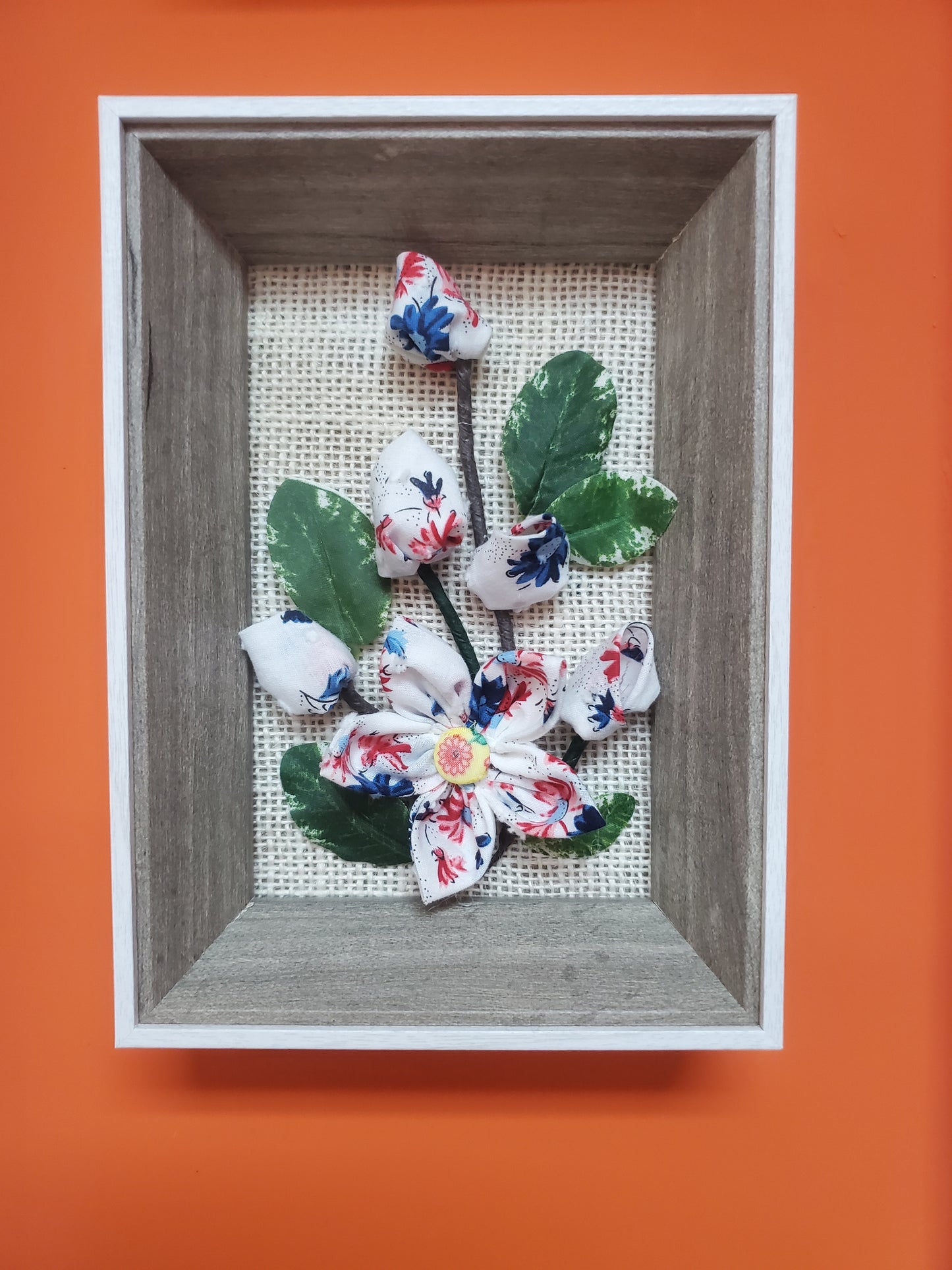 Handmade flowers and green leaves, put them in a picture frame, flowers are made of fabric.