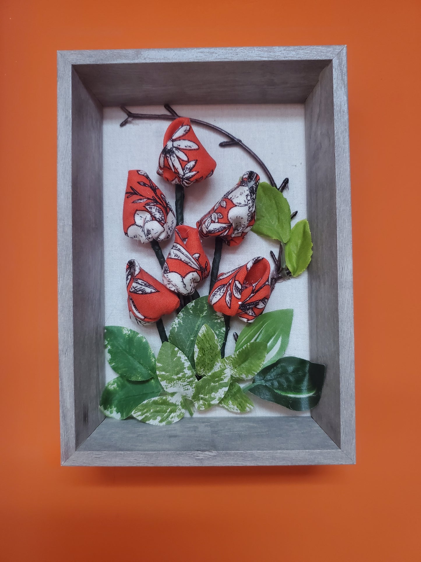 Handmade flowers and green leaves, put them in a picture frame, flowers are made of fabric.