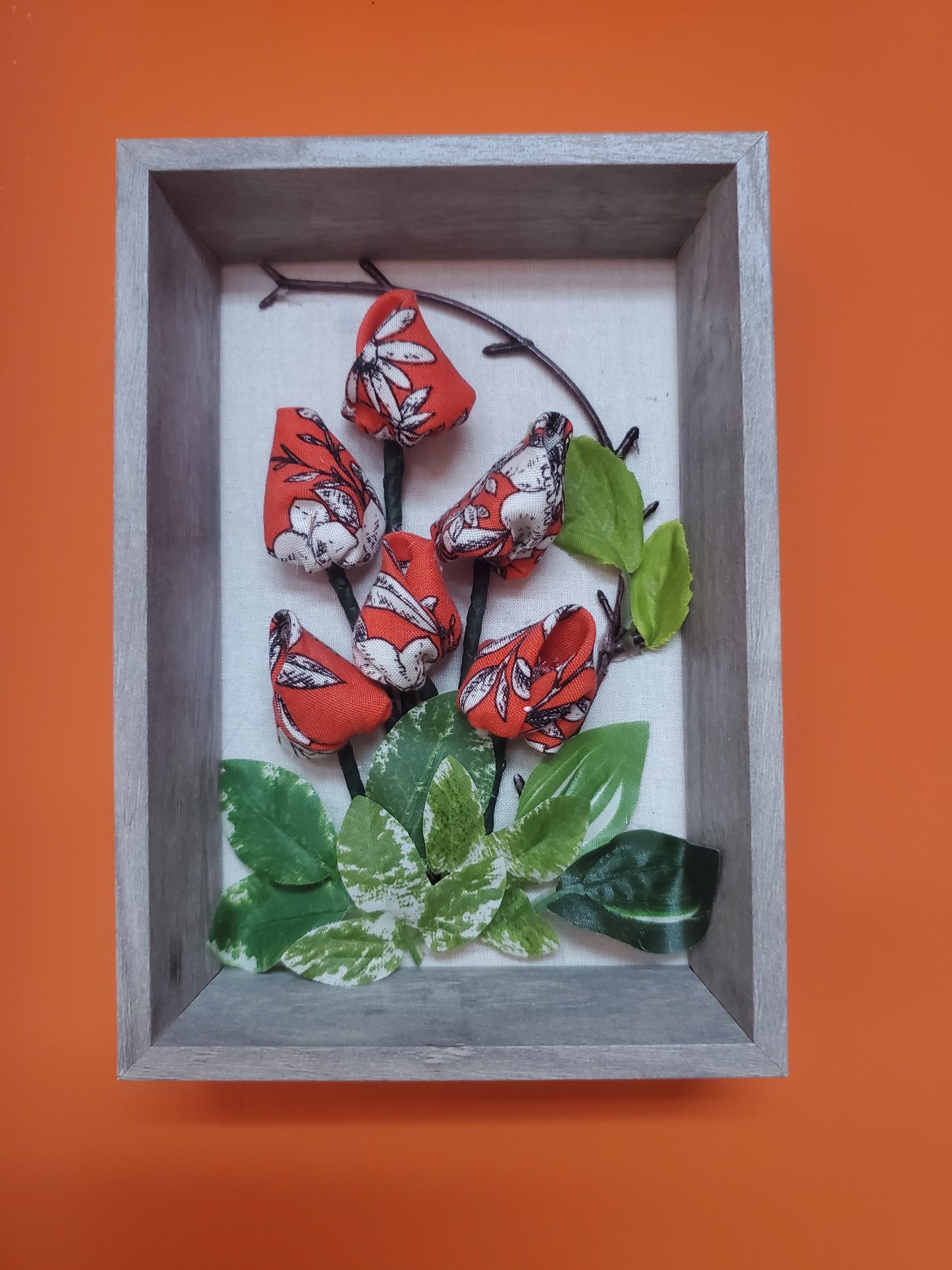 Handmade flowers and green leaves, put them in a picture frame, flowers are made of fabric.