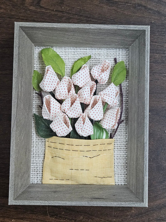Handmade flowers with pink flower pots and green leaves, put them in a picture frame, flowers are made of fabric.